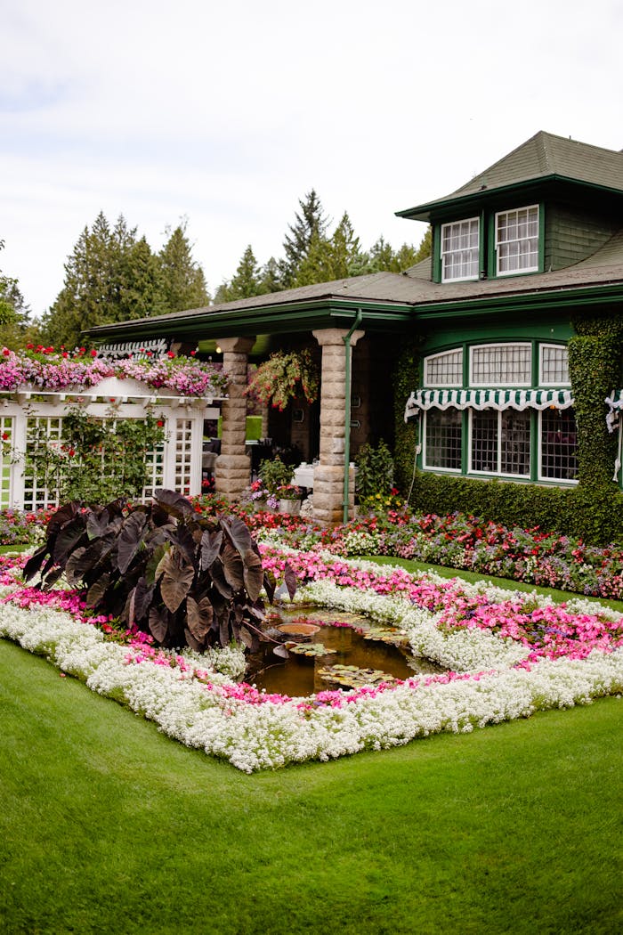who-we-are A beautifully landscaped garden with vibrant flowers in front of a classic green house, showcasing timeless elegance.